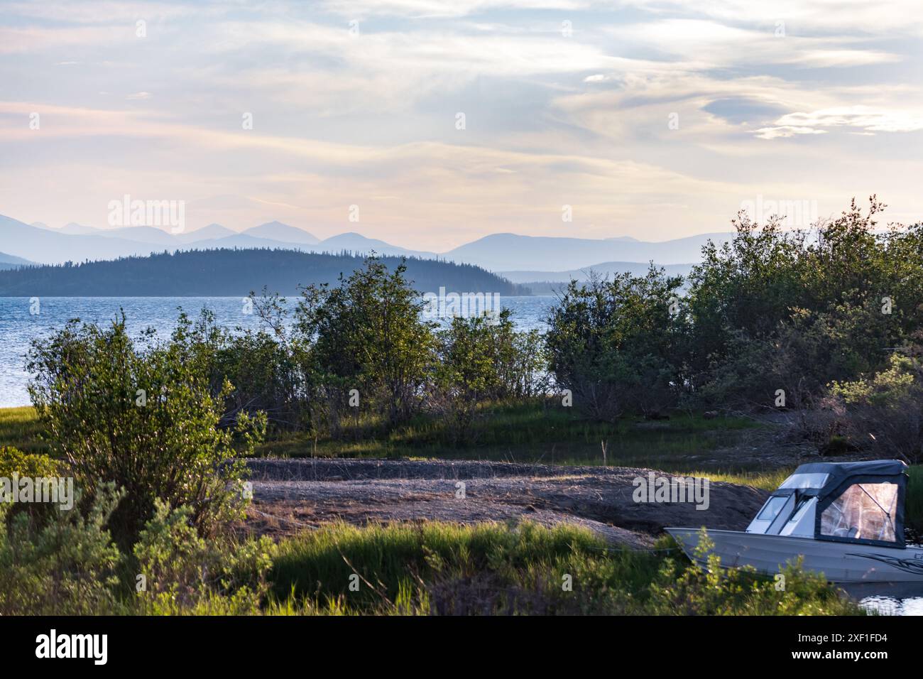 Blick auf den Sommer im Norden Kanadas mit ruhigem Blick auf den See und die Berge. Weißes Boot im Blick. Stockfoto