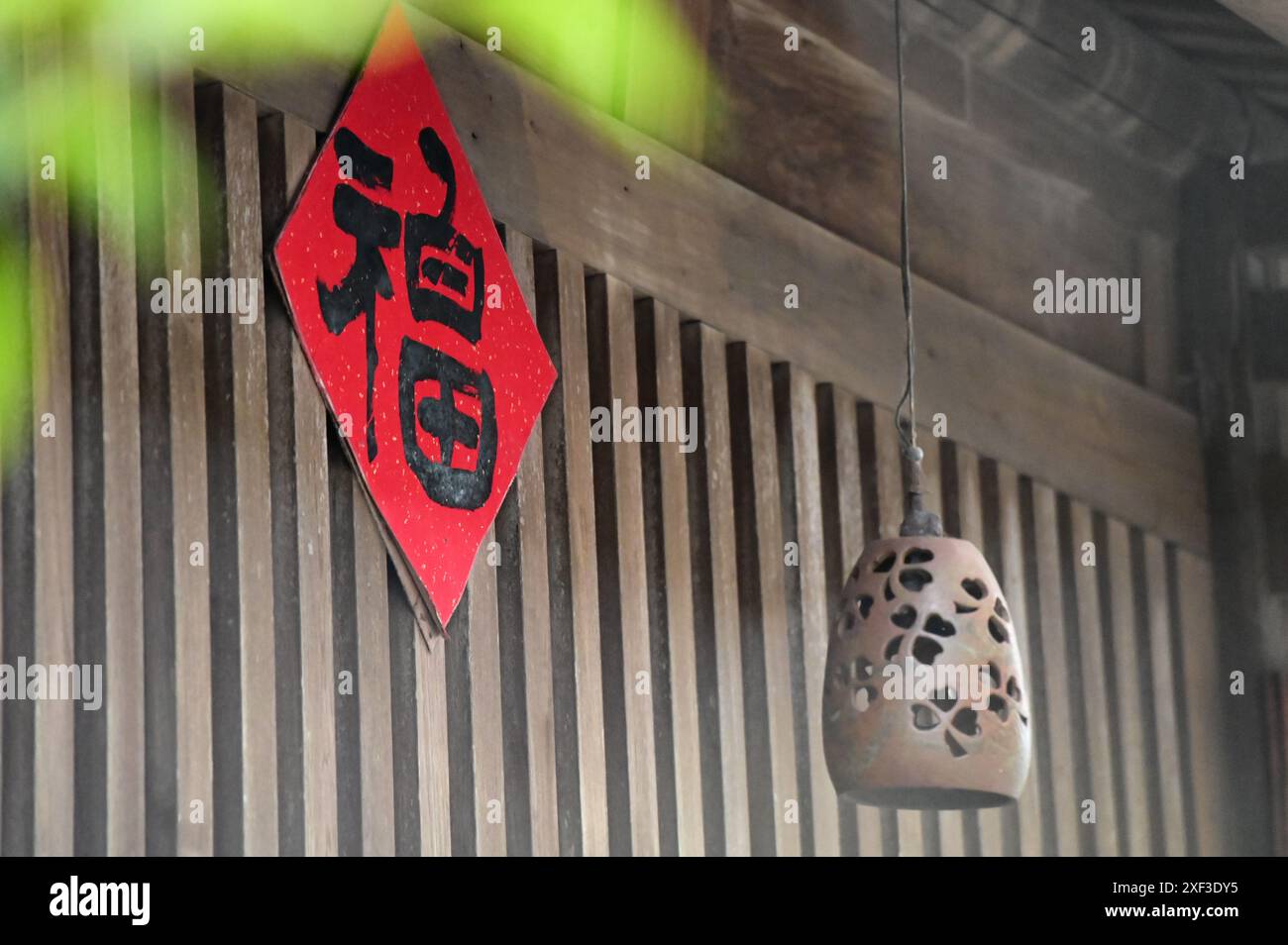 Ein Holzhaus strahlt Wärme aus mit seinen duftenden Holzwänden, roten „福“ („Fu“, „Good Fortune“) Frühlingskissen und keramischen Windklingeln. Stockfoto