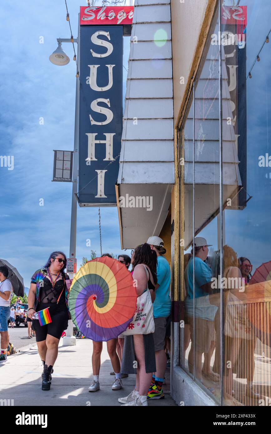 Die Leute stehen im Schatten des Shogun Sushi Restaurants an der Central Avenue, Route 66, und beobachten Pride Parade 2024, Albuquerque, New Mexico, USA. Stockfoto
