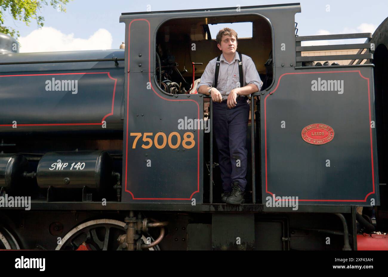 Feuerwehrmann, stehend auf der Fußplatte, im Fahrerhaus der Lokomotive Nr. 75008 Swiftsure, Tenterden Town Station, auf der Kent and East Sussex Railway Stockfoto