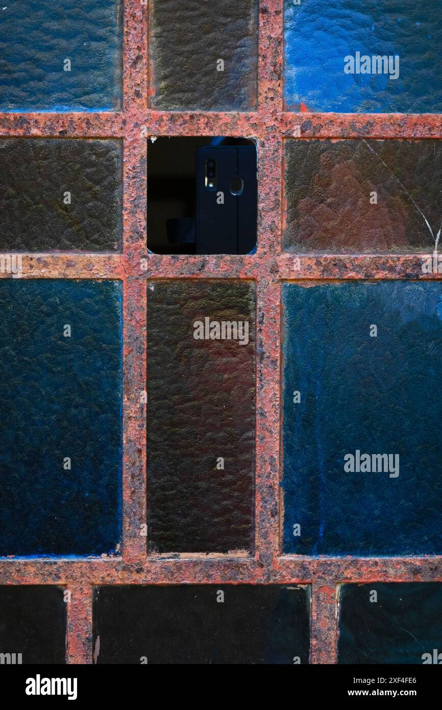 Altes rostiges Metallfenster mit mattiertem Glas in Blau und Braun Stockfoto