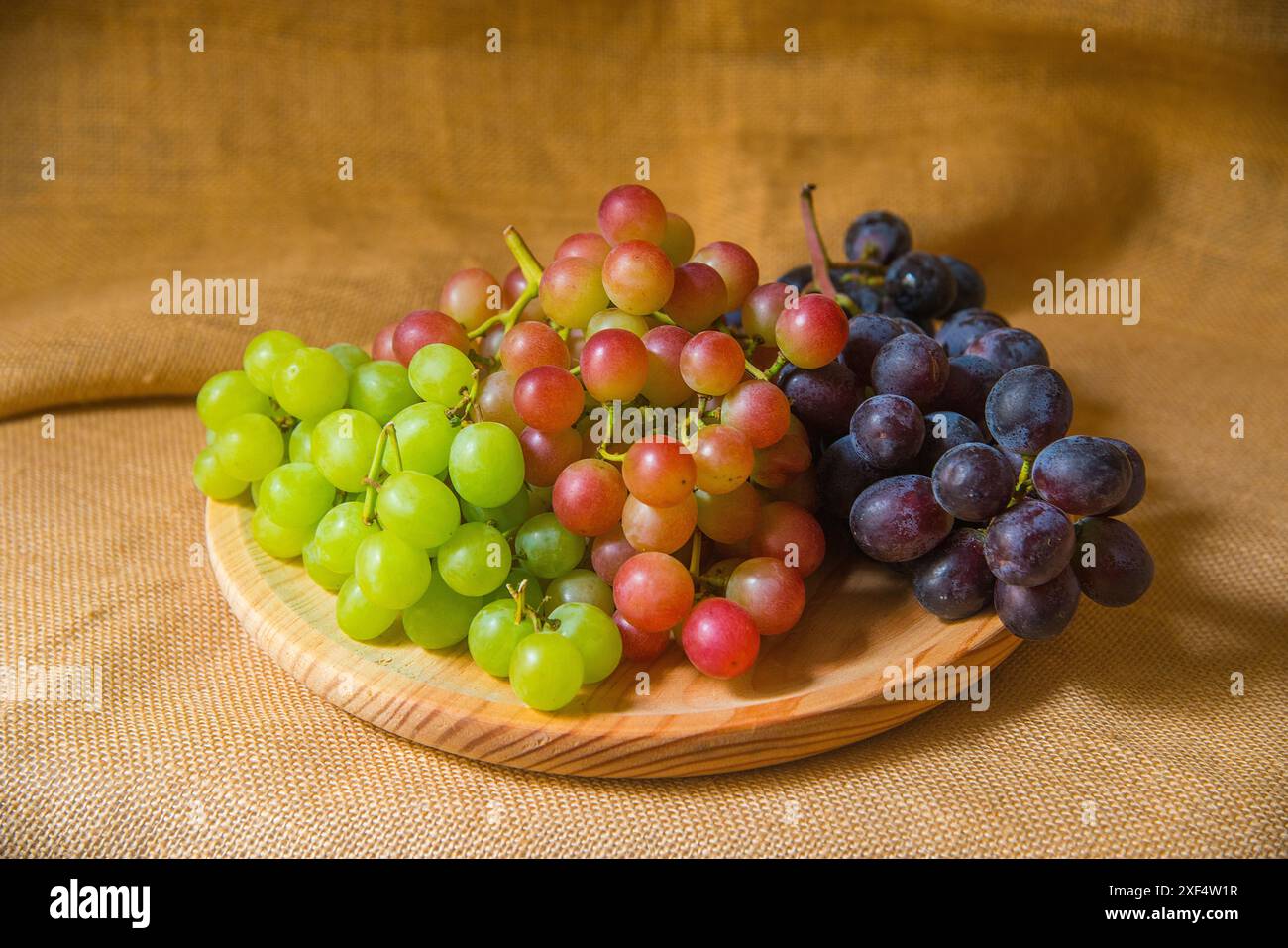 Trauben dreifarbiger Trauben auf Holzschale. Stockfoto