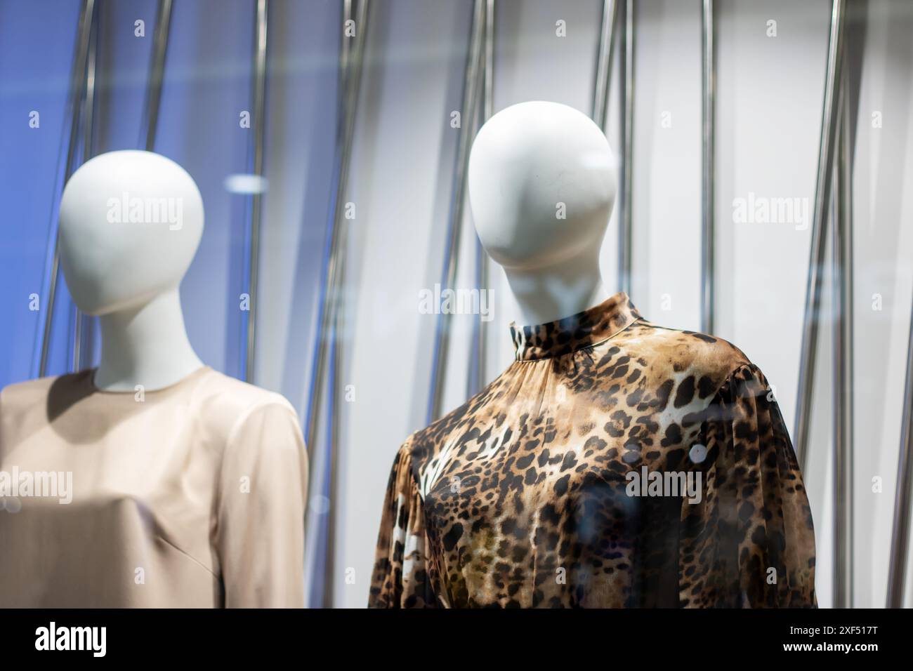 Zwei Schaufensterpuppen, die in Hemden mit Leopardenmuster gekleidet sind, werden in einem Schaufenster ausgestellt, in dem die neuesten Modeschöpfe präsentiert werden. Auf der Fensteranzeige wird ein angezeigt Stockfoto