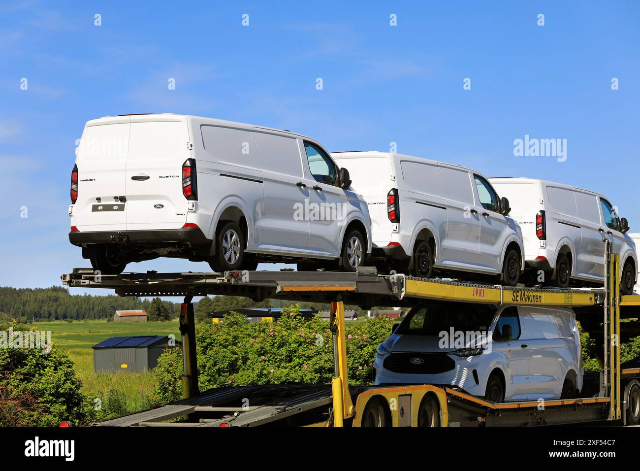 Der Lkw transportiert neue, weiße Ford Transit Custom Transporter auf einem Anhänger. Detail der Rückansicht. Salo, Finnland. Juni 2024. Stockfoto