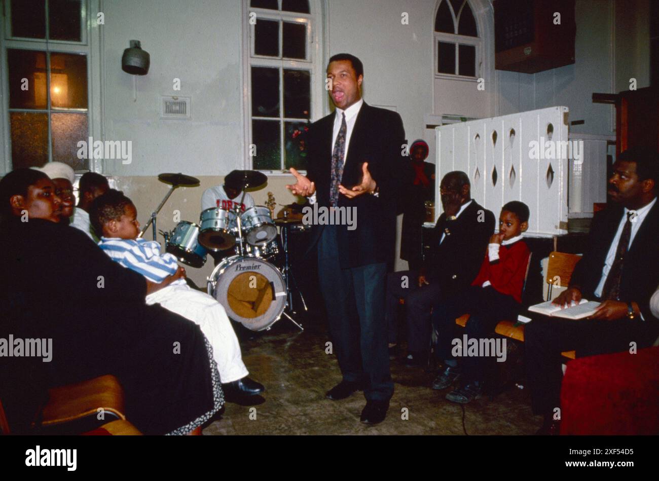 Afrikanische Kirche Großbritannien. Church of God of Prophecy, feurige Predigt nach dem Taufgottesdienst im Kirchensaal an der Tubbs Road. Der Prediger wurde von seiner Botschaft mitgerissen, er bewegt sich den Flur hoch und runter. Das Kirchentrommel-Kit im Hintergrund ist einsatzbereit, wenn Songbücher geöffnet werden. Harlesden, London, England um die 1995 1990er Jahre UK HOMER SYKES Stockfoto