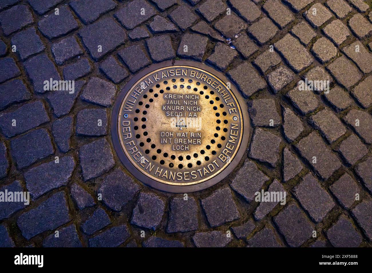 Bremer Loch am Bremer Marktplatz ist eine interaktive Spendeninstallation aus dem Jahr 2007. Es handelt sich um einen bronzenen Mannlochdeckel mit Münzschlitz, der beim Einlegen von Münzen die tierischen Stimmen der Bremer Stadtmusiker - Hahn, Katze, Hund und Esel - spielt. Der Erlös kommt jährlich sozialen Projekten in Bremen zugute. Bremer Loch auf dem Marktplatz. Das Bremer Loch dient als Spendengeldbox für die Wilhelm Kaisen Bürgerhilfe der Freien Hansestadt Bremen. Nach dem Einlegen einer Münze ist der typische Ruf eines Bremer Stadtmusikers zu hören. Esel, Hund, Katze oder Hahn. Bremen, Deutschland Stockfoto