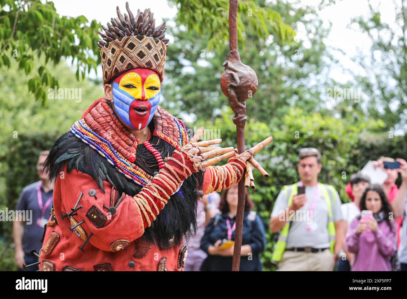 London, Großbritannien. Juli 2024. Im Lion King Anniversary Garden Show Garden, Star von Disney's The Lion King in the West End, spielt Thenjiwe Nofemele den berühmten „Circle of Life“ in ihrem vollen Rafiki-Kostüm, begleitet von fliegenden Vogelpuppen und Darstellern, um das 25. Jahr der Show im Lyceum Theatre zu feiern. Pressevorschau beim RHS Hampton Court Palace Garden Festival (ehemals Hampton Court Flower Show). Das Festival wird am Dienstag, den 2. Juli, für die Öffentlichkeit geöffnet, um das Beste der Gartenarbeit im Sommer zu feiern. Quelle: Imageplotter/Alamy Live News Stockfoto