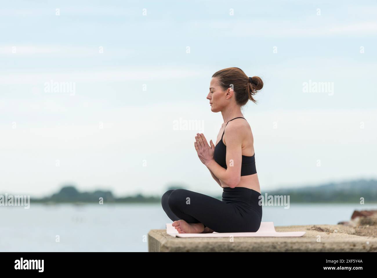 Sportliche Frau, die draußen meditiert. Stockfoto