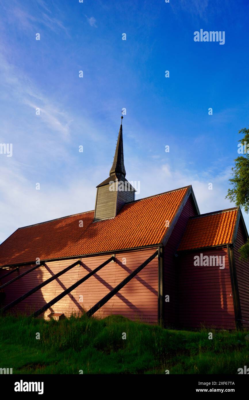 Eine senkrechte historische Holzstabkirche mit rotem Dach und Kirchturm unter klarem blauen Himmel bei Kvernes in Averoy, Norwegen Stockfoto