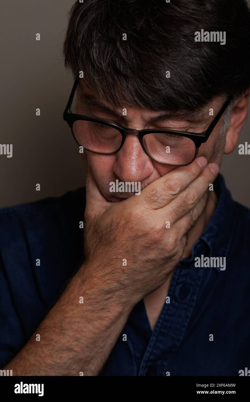 Mann mittleren Alters mit Hand auf Mund wegen Zahnschmerzen Stockfoto