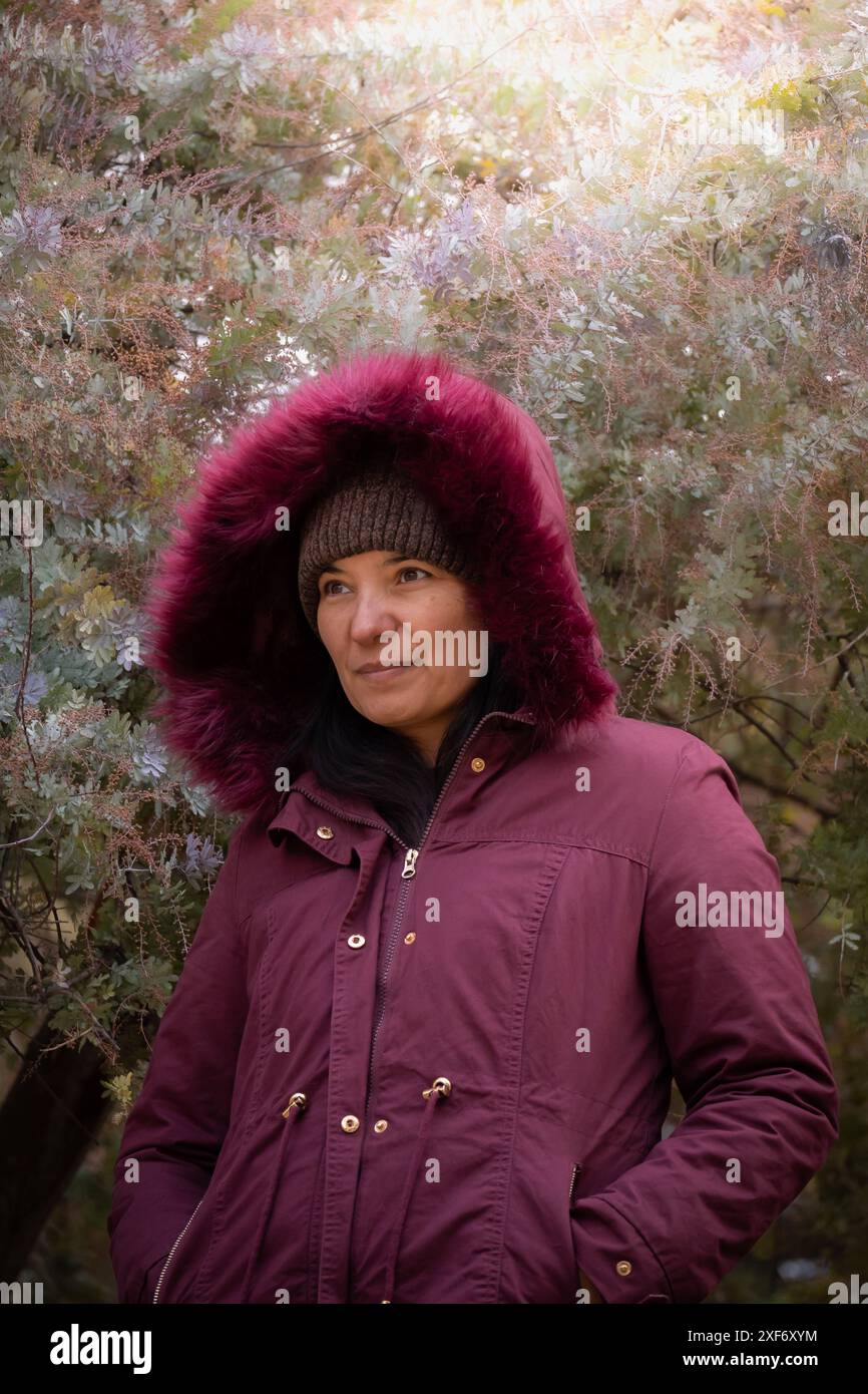 Lateinische Frau mittleren Alters in der Nähe einiger Bäume im Herbst. Stockfoto