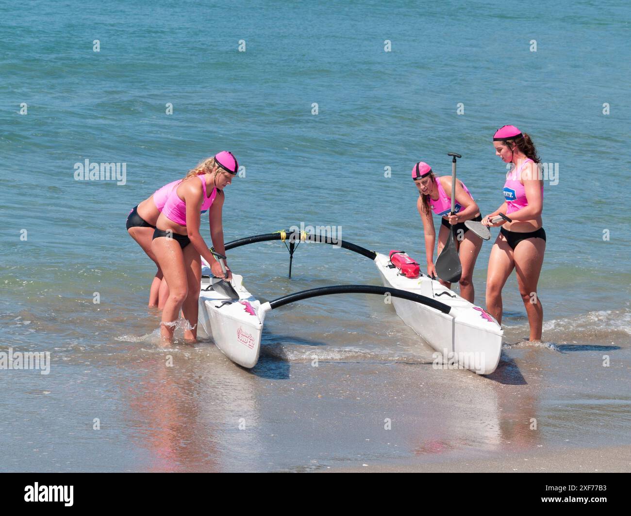 Tauranga Neuseeland - 28. Januar 2012; Frauen in rosa Streifen Surf Kanu Paddler lassen Wasser in Surf Club Event. Stockfoto
