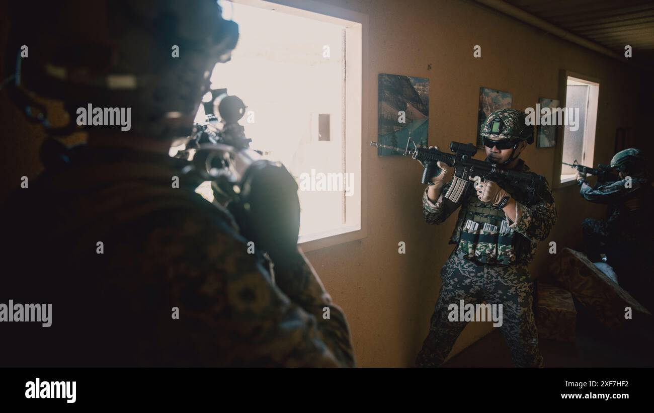 US-Marines, die dem Bataillon-Landungsteam 1/5, 15. Marine-Expeditionstruppe zugewiesen sind, und malaysische Soldaten, die dem 8. Bataillon (Para), dem Royal Ranger Regiment, der 10. Fallschirmbrigade, zugewiesen wurden, halten Sicherheit an einem Fenster im Infanterie-Tauchtrainer im Marine Corps Training Area Bellows, Waimanalo, Hawaii, für Übung Rim of the Pacific 2024, 29. Juni 2024. Das IIT bot immersive szenarienbasierte Schulungen an, um Marines und Partnernationen in Infanterie-Taktiken zu bewerten. 29 Nationen, 40 Überlandschiffe, drei U-Boote, 14 nationale Landstreitkräfte, mehr als 150 Flugzeuge und 25.000 Personen Stockfoto