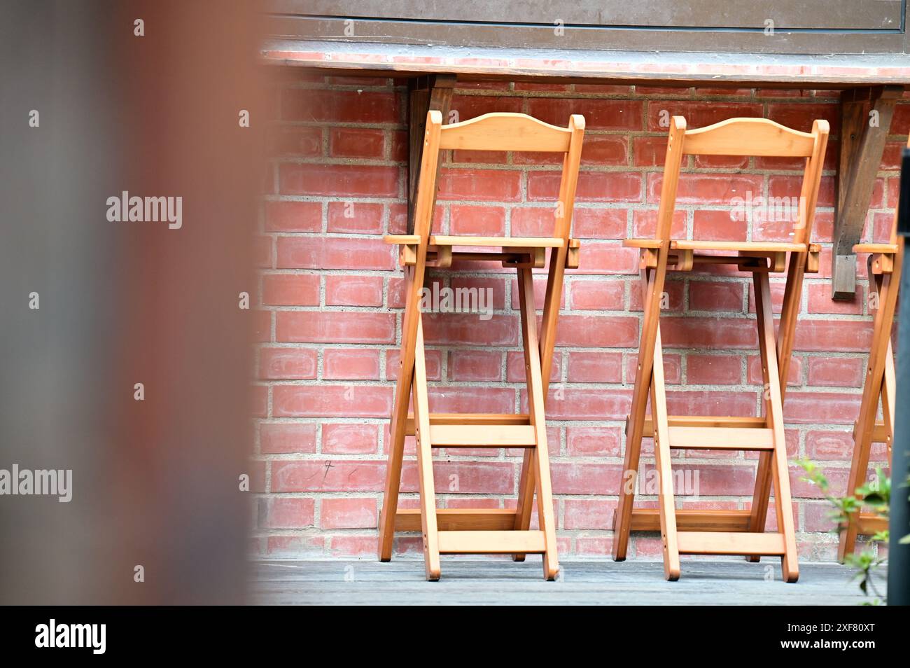 Klarer Tag, rote Backsteinwände im Freien, Sonnenlicht, begleitet von ein paar Klapphockern. Stockfoto