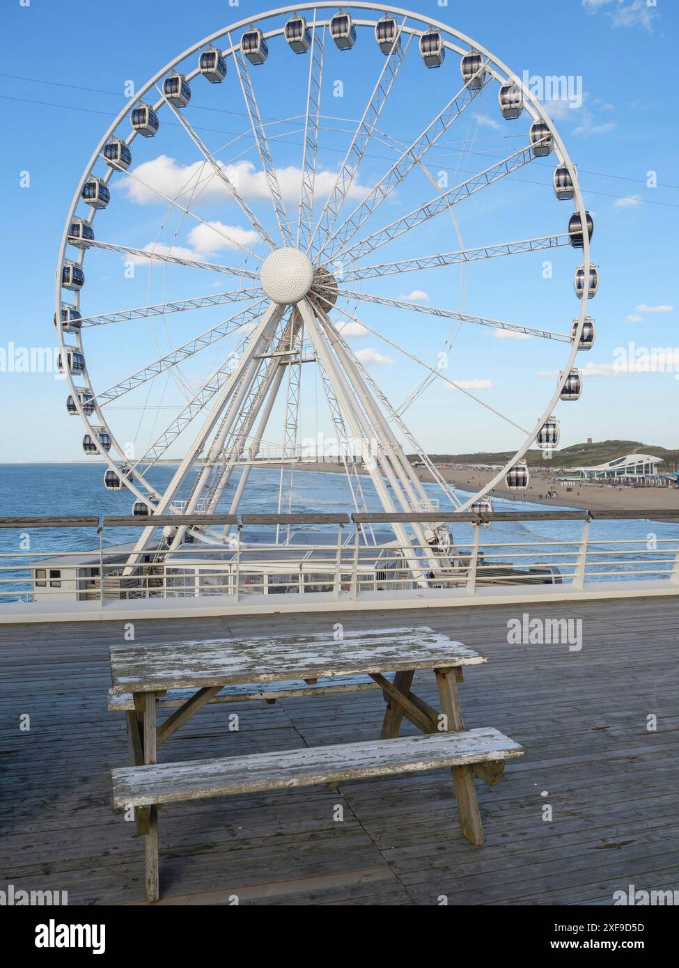Riesenrad am Pier in der Nähe einer alten Holzbank mit dem Meer im Hintergrund, scheveningen, niederlande Stockfoto