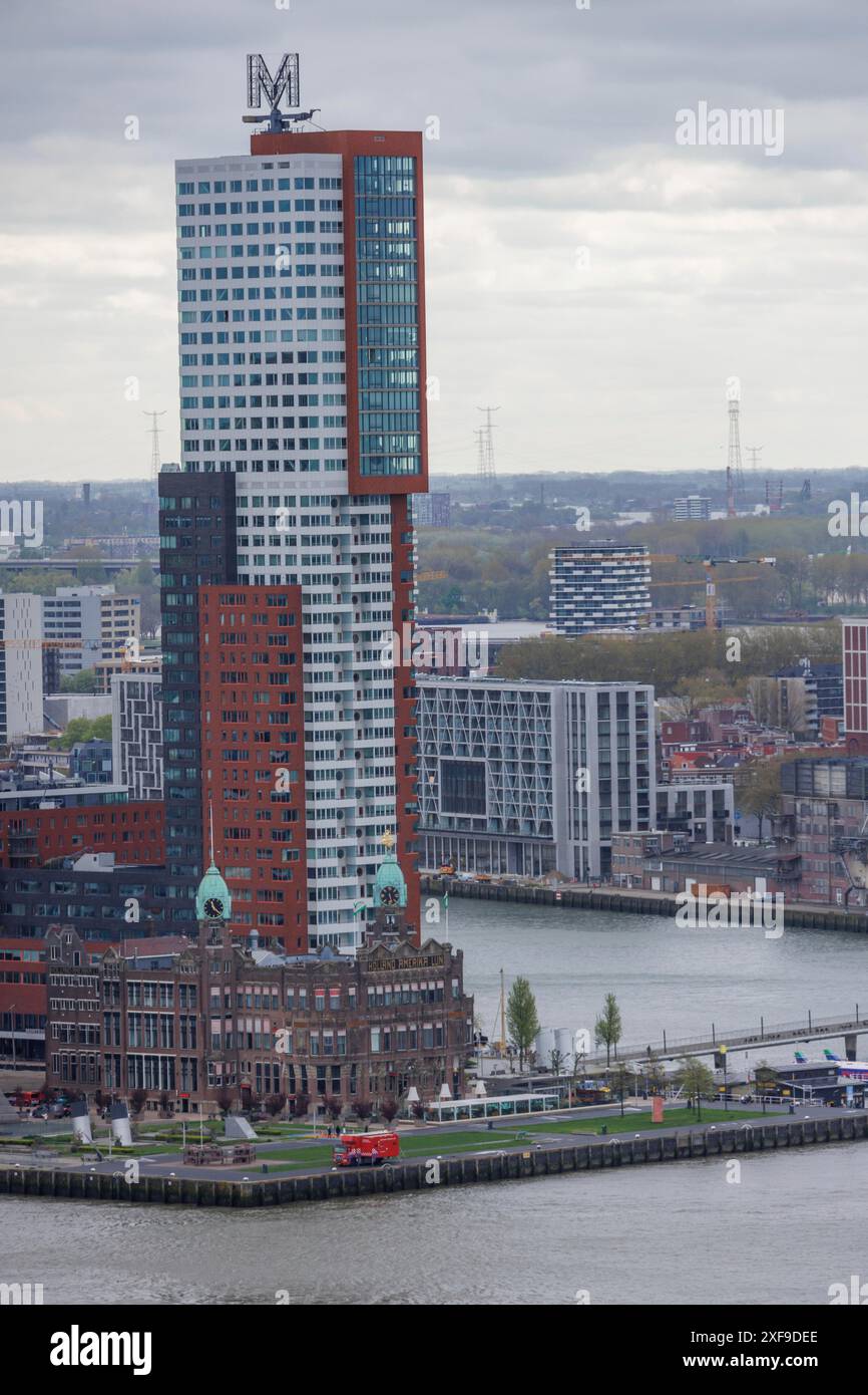 Schlanker, hoher Turm inmitten einer städtischen Umgebung mit modernen Gebäuden unter bewölktem Himmel, Rotterdam, Niederlande Stockfoto