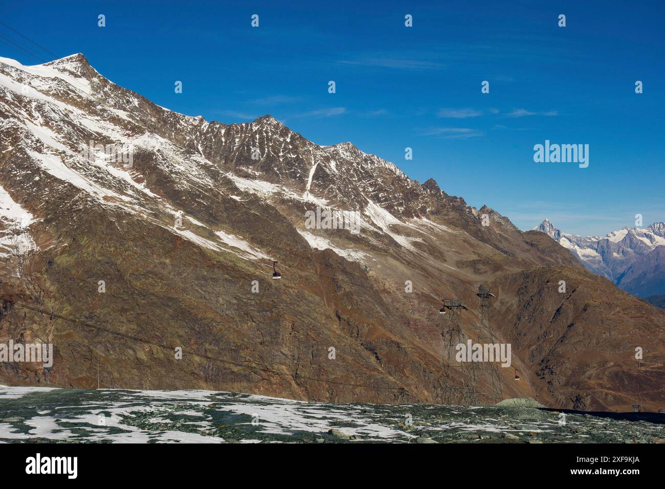 Bergkette mit schneebedeckten Gipfeln und sichtbaren Seilbahnen unter klarem blauem Himmel, saas Fee, schweiz Stockfoto