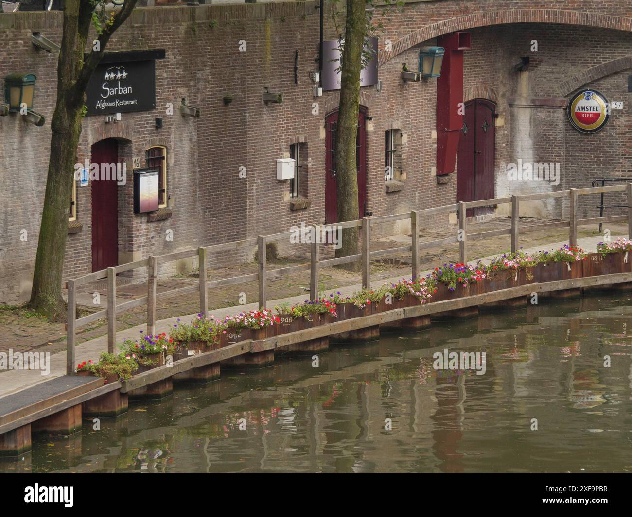 Ruhige Promenade entlang eines Kanals mit blühenden Blumen und historischen Gebäuden, utrecht, niederlande Stockfoto