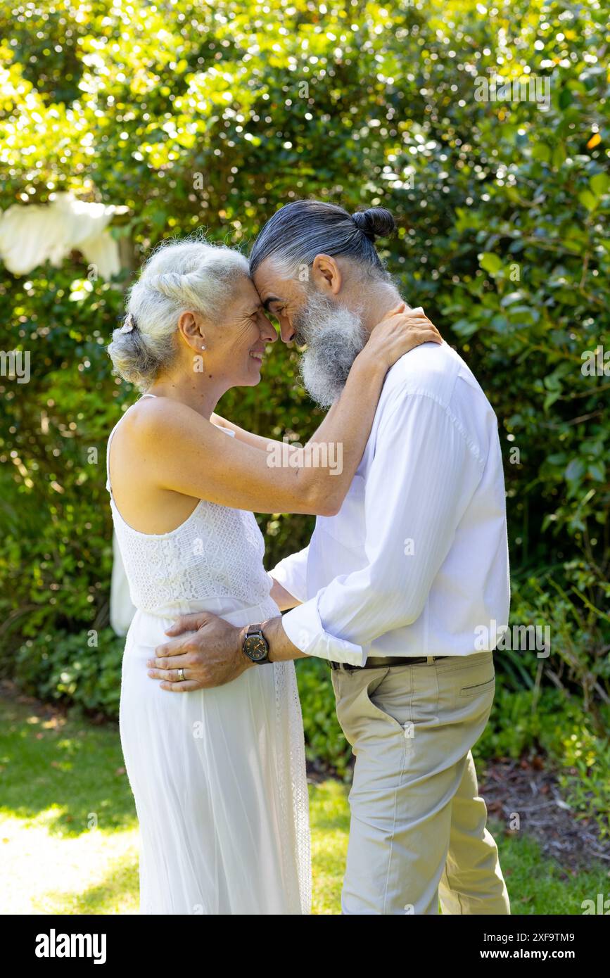 Ältere Braut und Bräutigam umarmen und lächeln im Garten, bei der Hochzeit Stockfoto