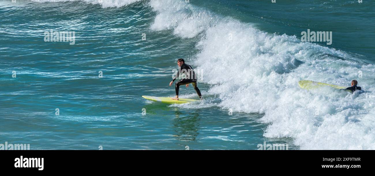 Ein Panoramabild eines Surfers am Great Western Beach in Newquay in Cornwall in Großbritannien. Stockfoto