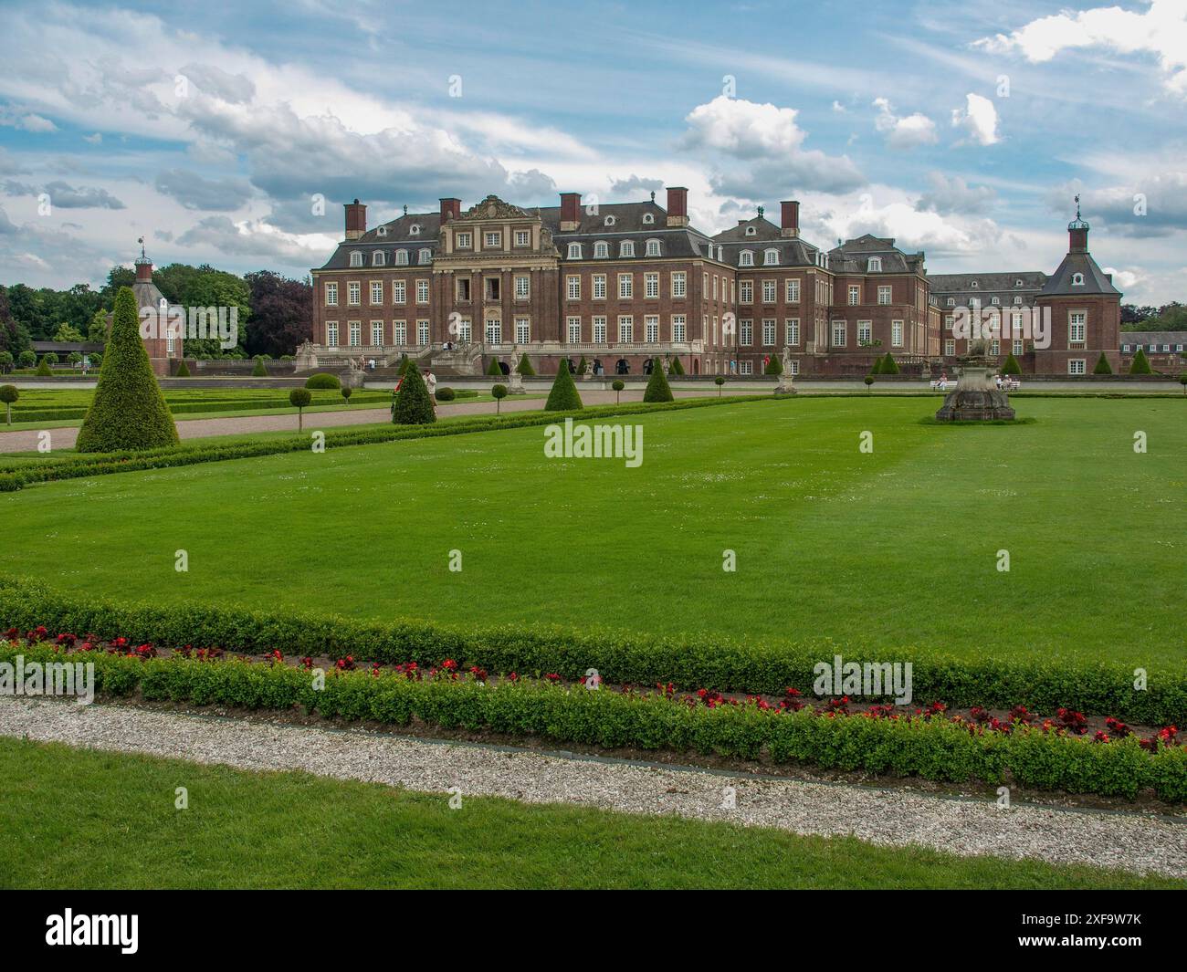 Ein großes Schloss im Hintergrund, umgeben von gepflegten Rasenflächen und dekorativen Gärten unter teilweise bewölktem Himmel, nordkirchen, münsterland, deutschland Stockfoto