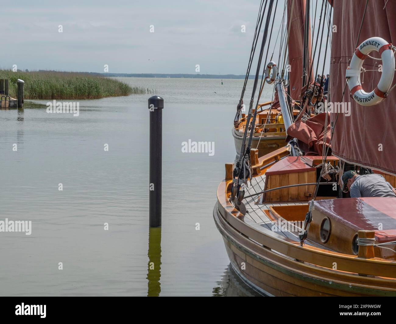 Verankerte Holzboote auf einem ruhigen See mit Schilf und bewölktem Himmel, ahrenshoop, zingst, Ostsee, Deutschland Stockfoto