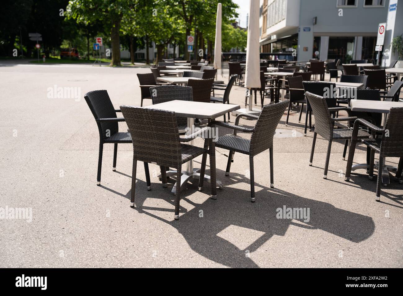 Leere Tische vor einem Café laden an einem sonnigen Tag zum Sitzen ein, sich auszuruhen und einen Drink oder Essen zu sich zu nehmen. Niedrige Tiefe von fi Stockfoto
