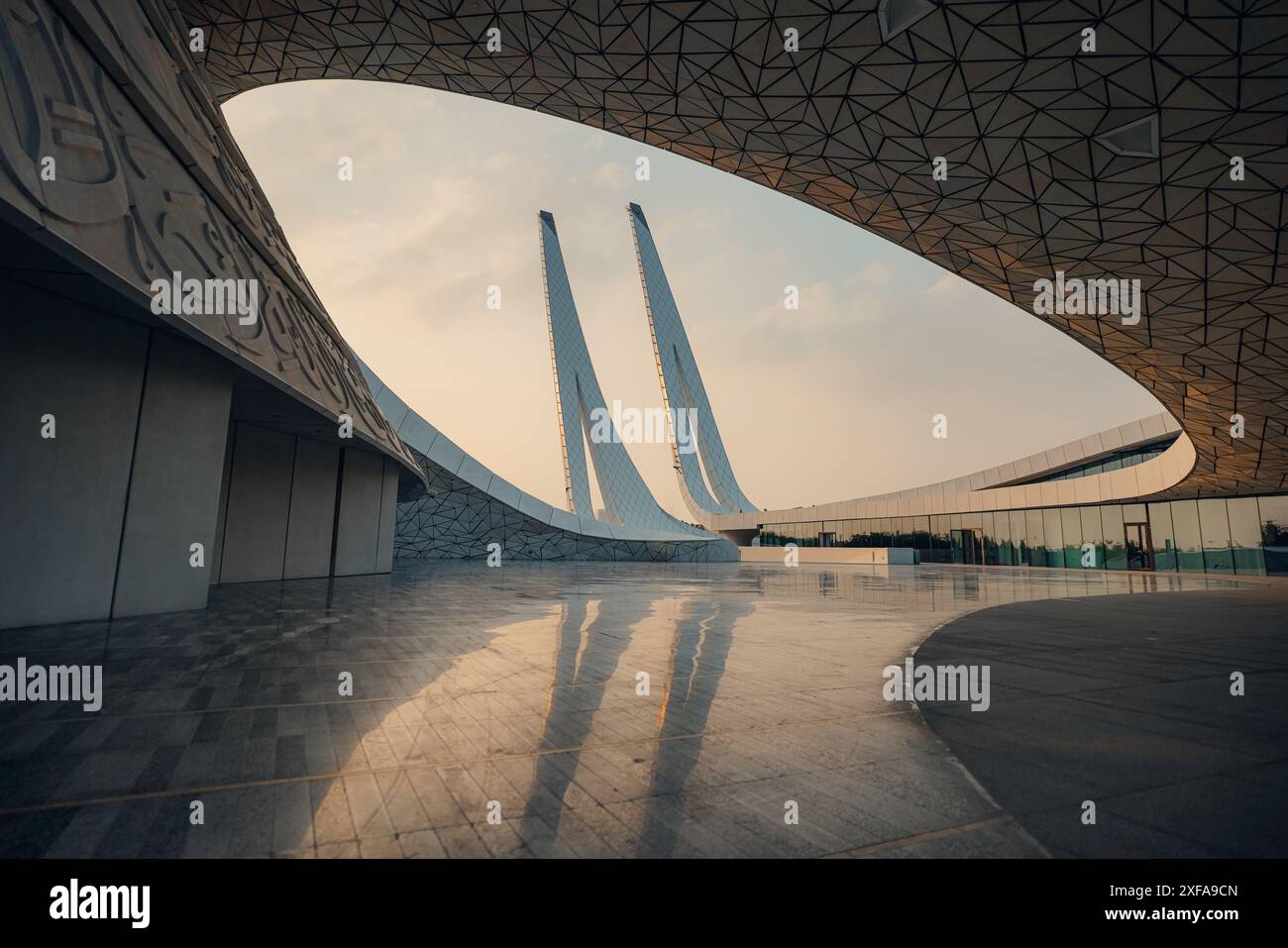 Modernes architektonisches Design mit geschwungenen Linien und reflektierenden Oberflächen bei Sonnenuntergang Stockfoto