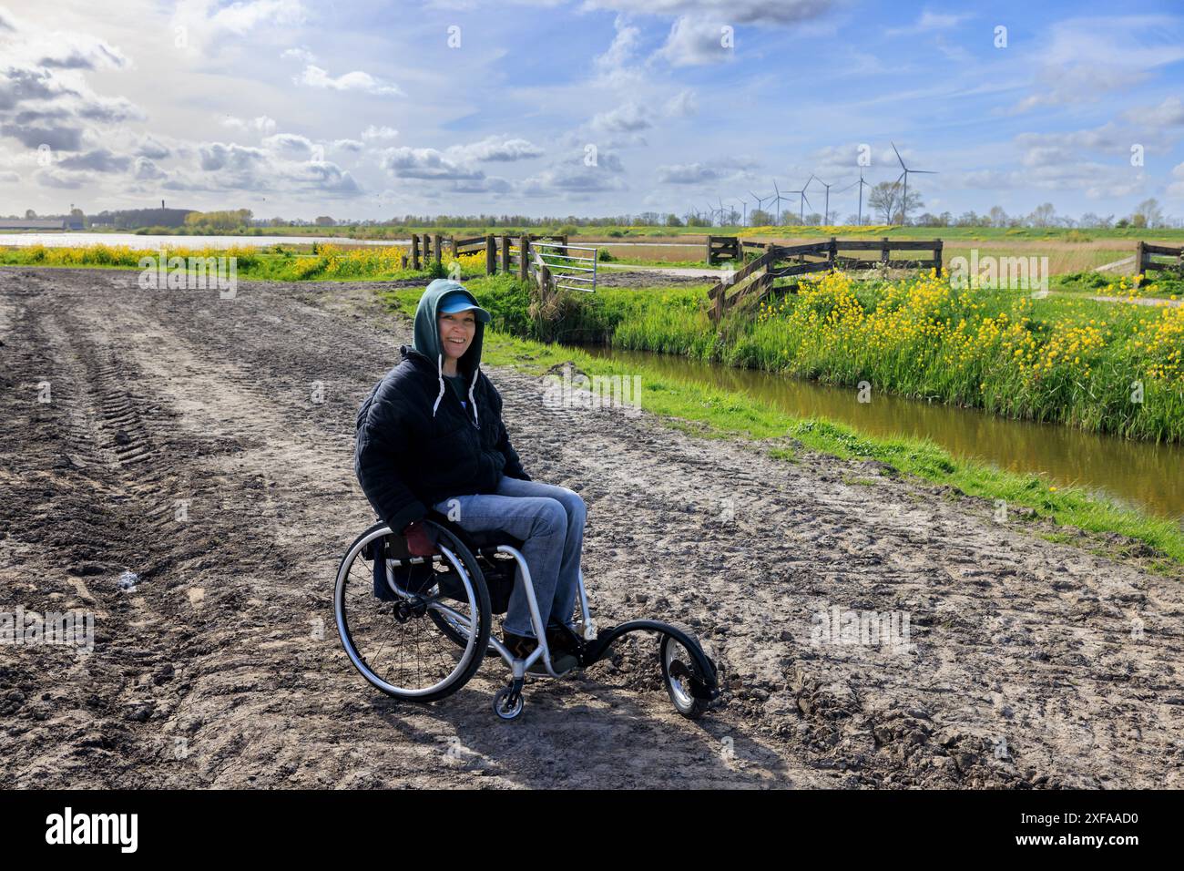 Eine junge Frau im Rollstuhl läuft auf einer schwierigen Straße auf dem Land Stockfoto