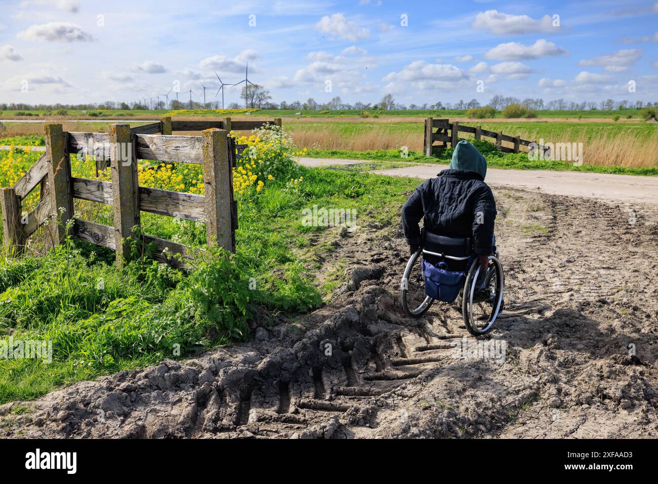 Eine junge Frau im Rollstuhl läuft auf einer schwierigen Straße auf dem Land Stockfoto