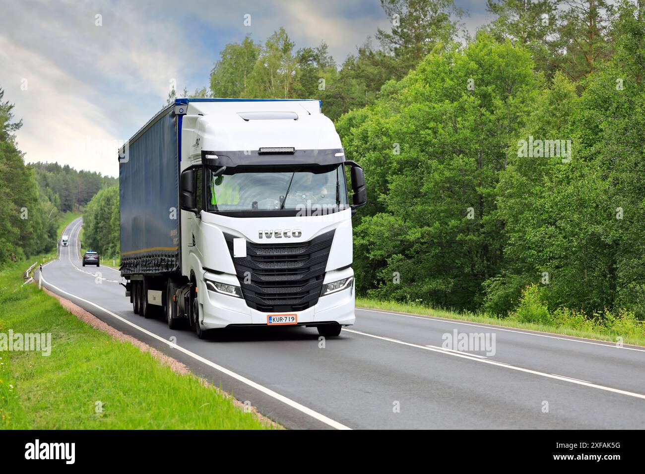 Der weiße Iveco S-Way-Lkw zieht an einem Sommertag den Auflieger entlang der Autobahn 52 bergauf. Salo, Finnland. Juni 2024. Stockfoto