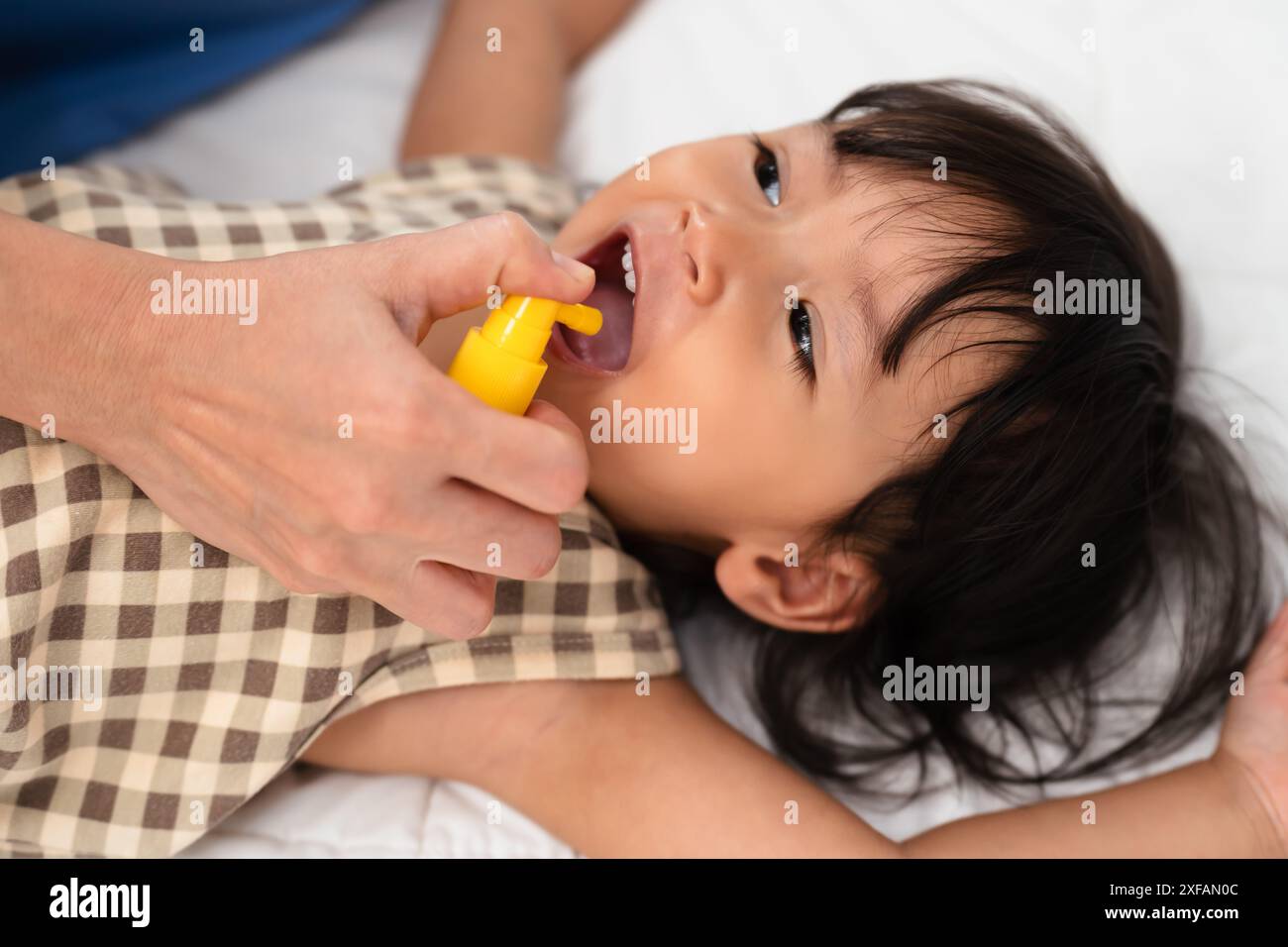 Mutter oder Arzt sprüht Medikamente im Mund eines Kleinkindes. Behandlungskonzept für Baby-Halsschmerzen Stockfoto