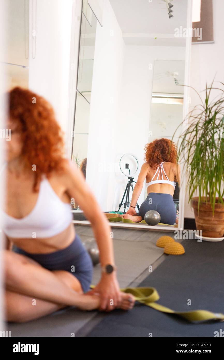 Yoga- und Pilates-Lehrerin in ihrem Yoga-Studio, die eine Klasse im Spiegel reflektiert Stockfoto