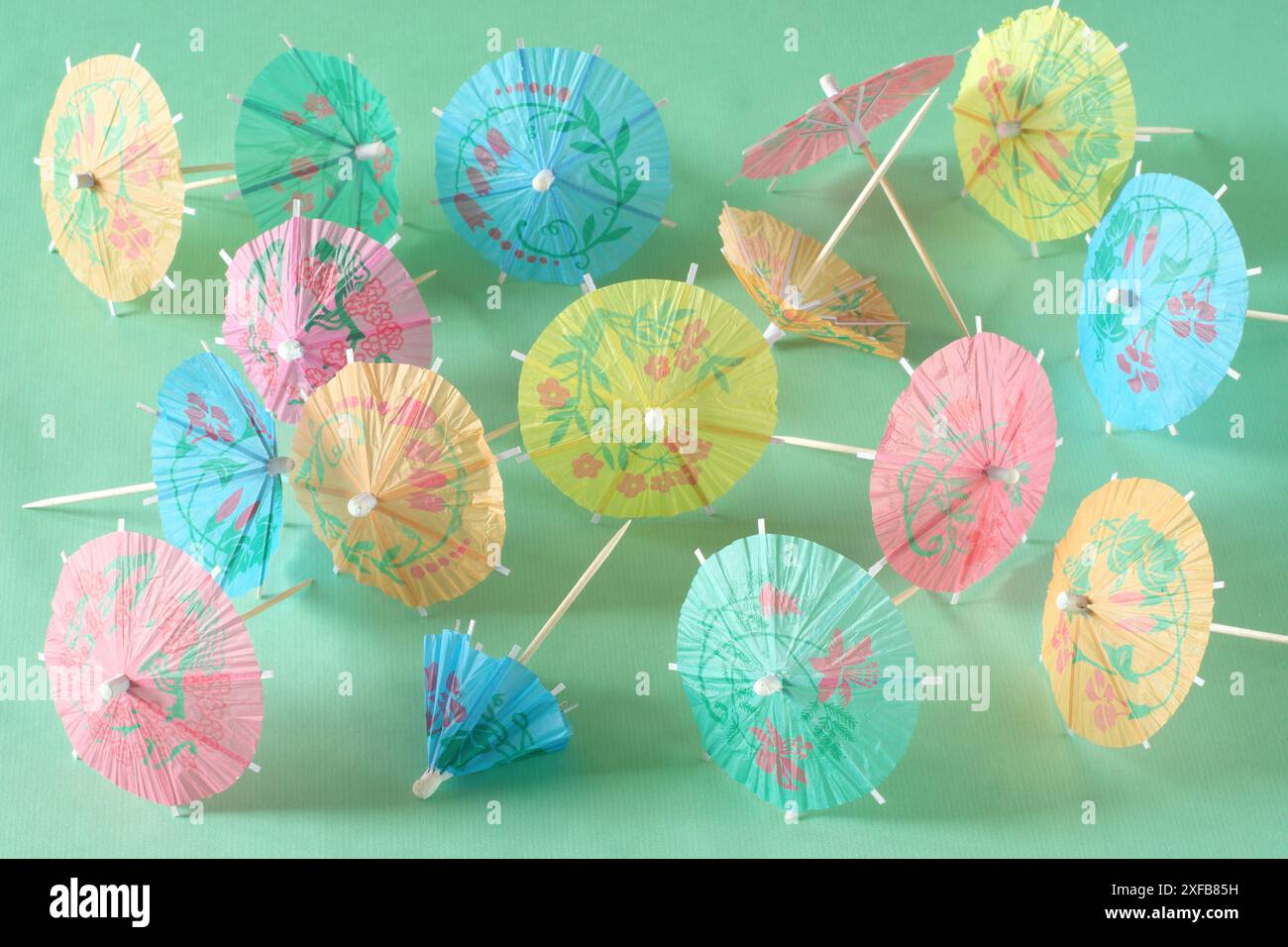 Mehrfarbige Cocktailschirme, Frühlings- und Sommersymbol, pastellgrüner Hintergrund, geringe Schärfentiefe Stockfoto