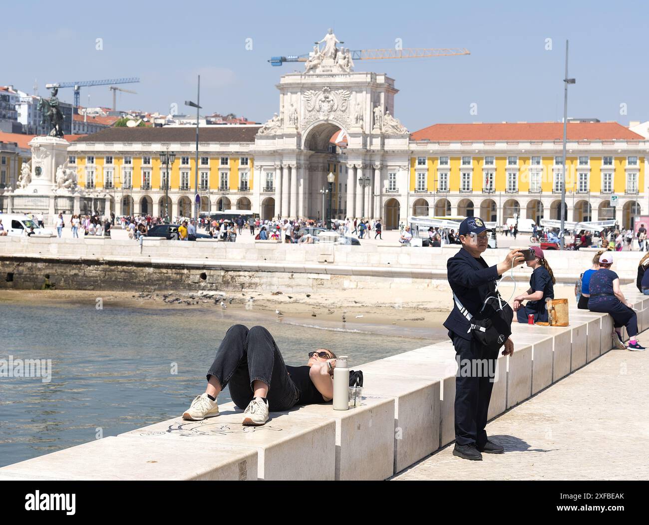 Lissabon Portugal: Ausländische Touristen machen Selfie am Handelsplatz am Meer. Mädchen, das sich an der Wand entspannt. Stockfoto