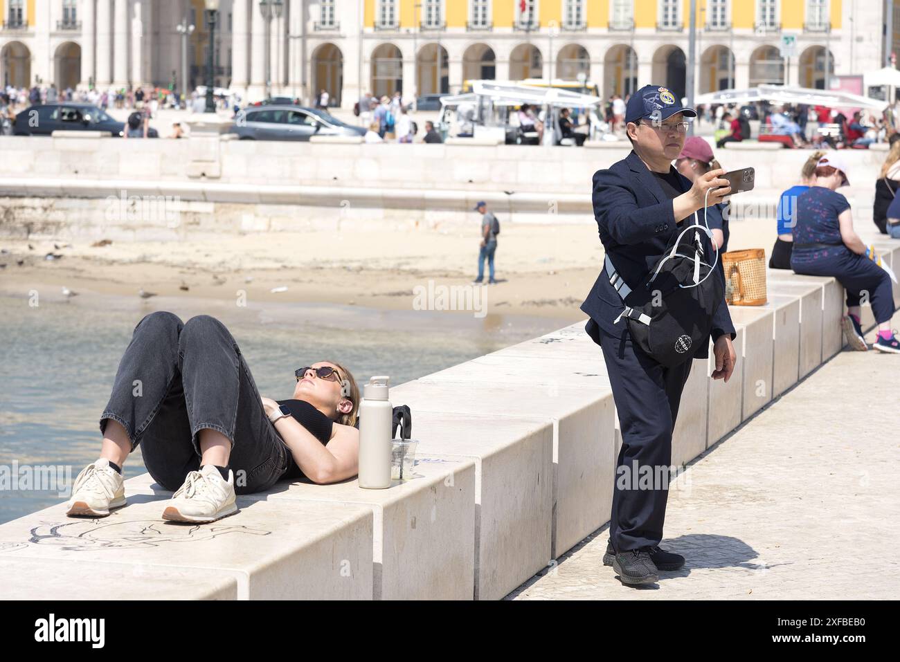 Lissabon Portugal: Ausländische Touristen machen Selfie am Handelsplatz am Meer. Mädchen, das sich an der Wand entspannt. Stockfoto