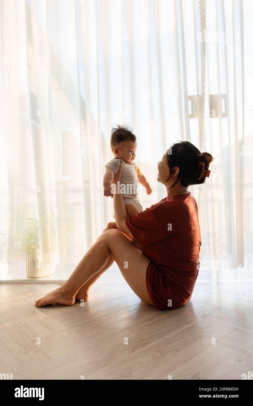 Eine Frau, die auf dem Boden sitzt und ein Baby hält Stockfoto