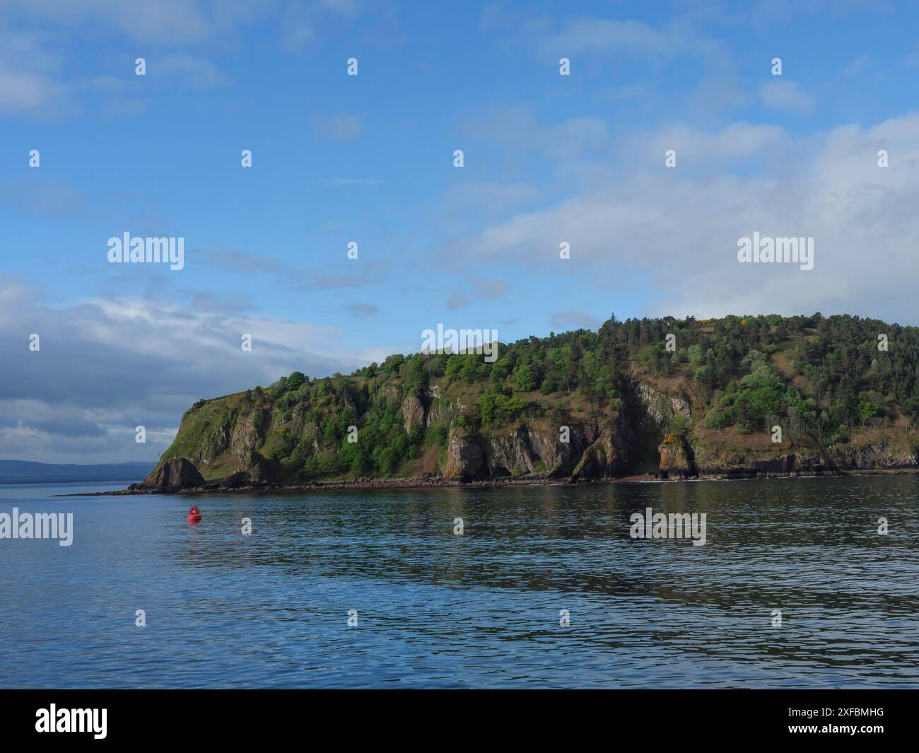 Küstenlandschaft mit hügeligem Ufer und Bäumen im Vordergrund, ruhigem Meer und blauem Himmel, Inverness, Schottland, Großbritannien Stockfoto