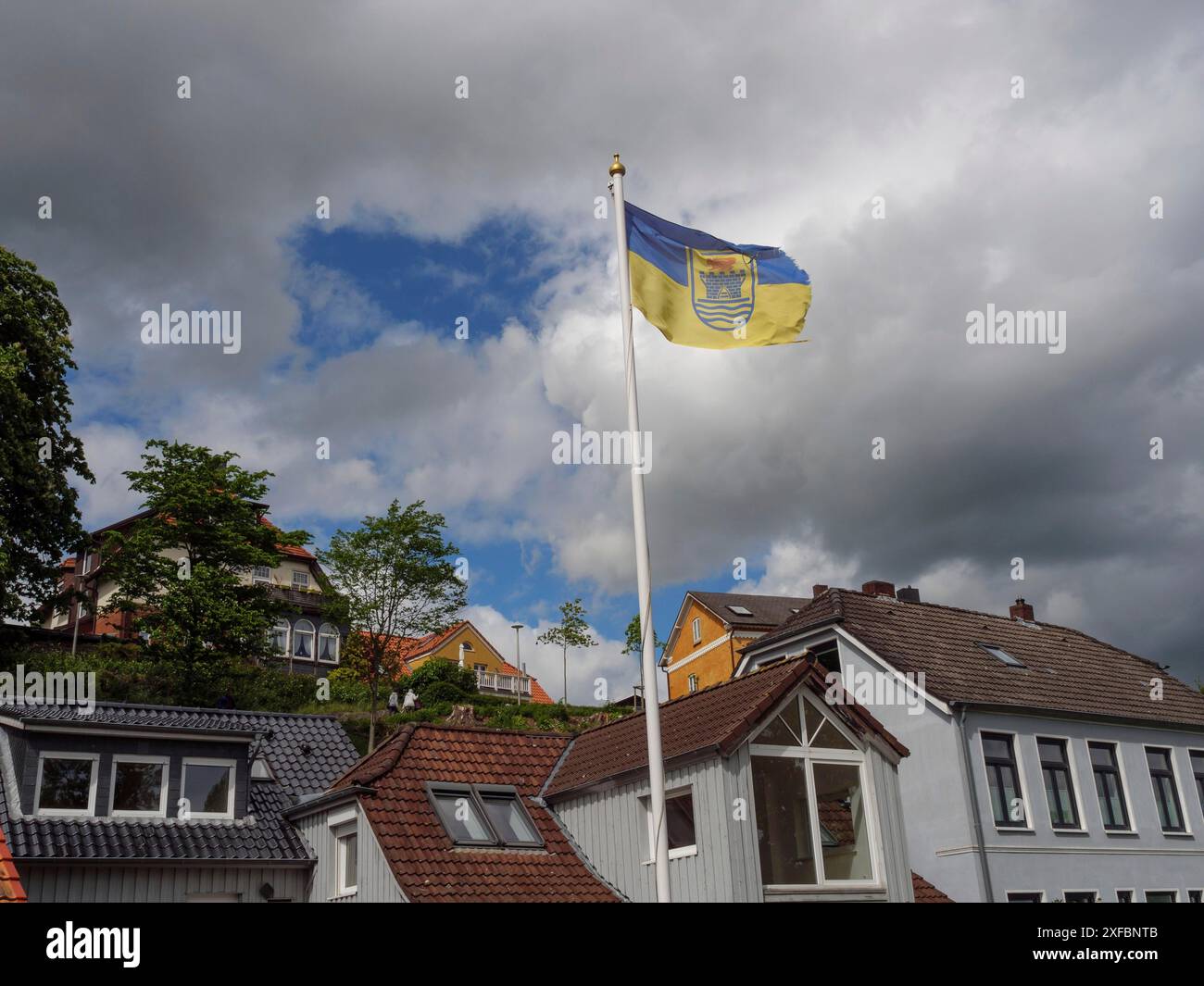 Die Flagge fliegt über einem Wohnviertel mit modernen und traditionellen Häusern unter bewölktem Himmel, Eckernförde, Schlewsiwg-holstein, Deutschland Stockfoto