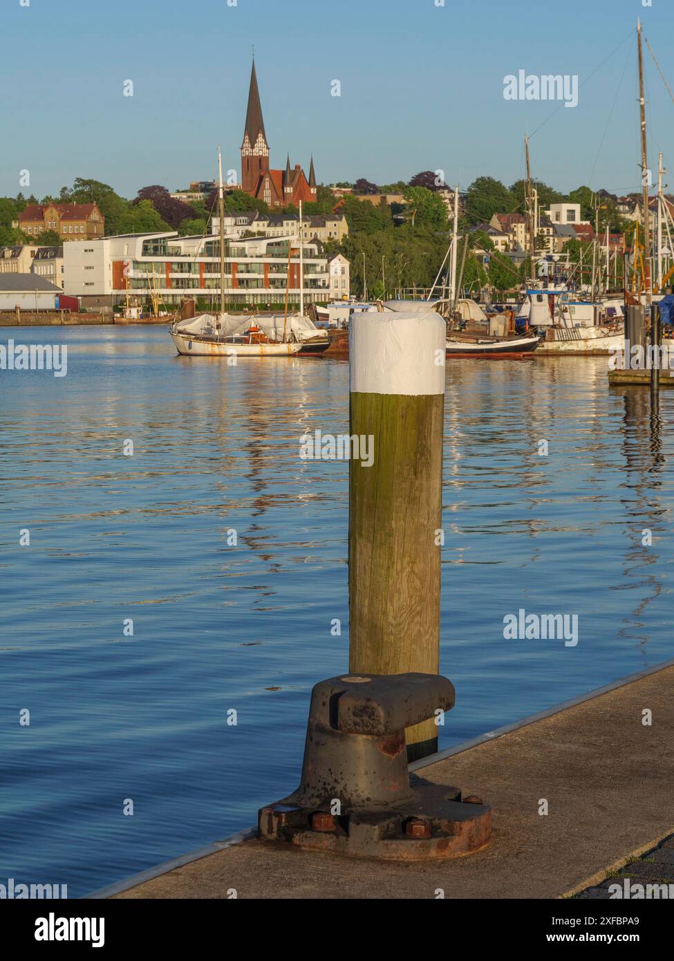 Hafenbereich mit Holzpfosten im Vordergrund, Boote und Kirche im Hintergrund, flensburg, schleswig-holstein, deutschland Stockfoto