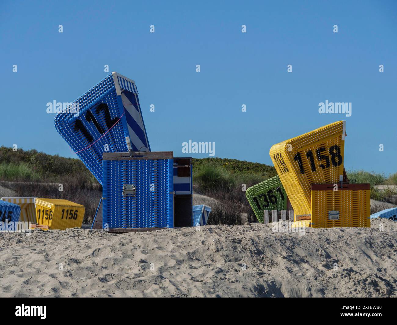 Liegestühle in gelb und blau auf einem Sandhügel Stockfoto