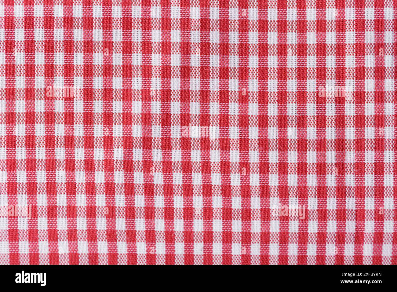 Ein rot-weiß karierter Stoff. Das karierte Muster ist sehr repetitiv und kräftig, die Farben sind hell. Stockfoto