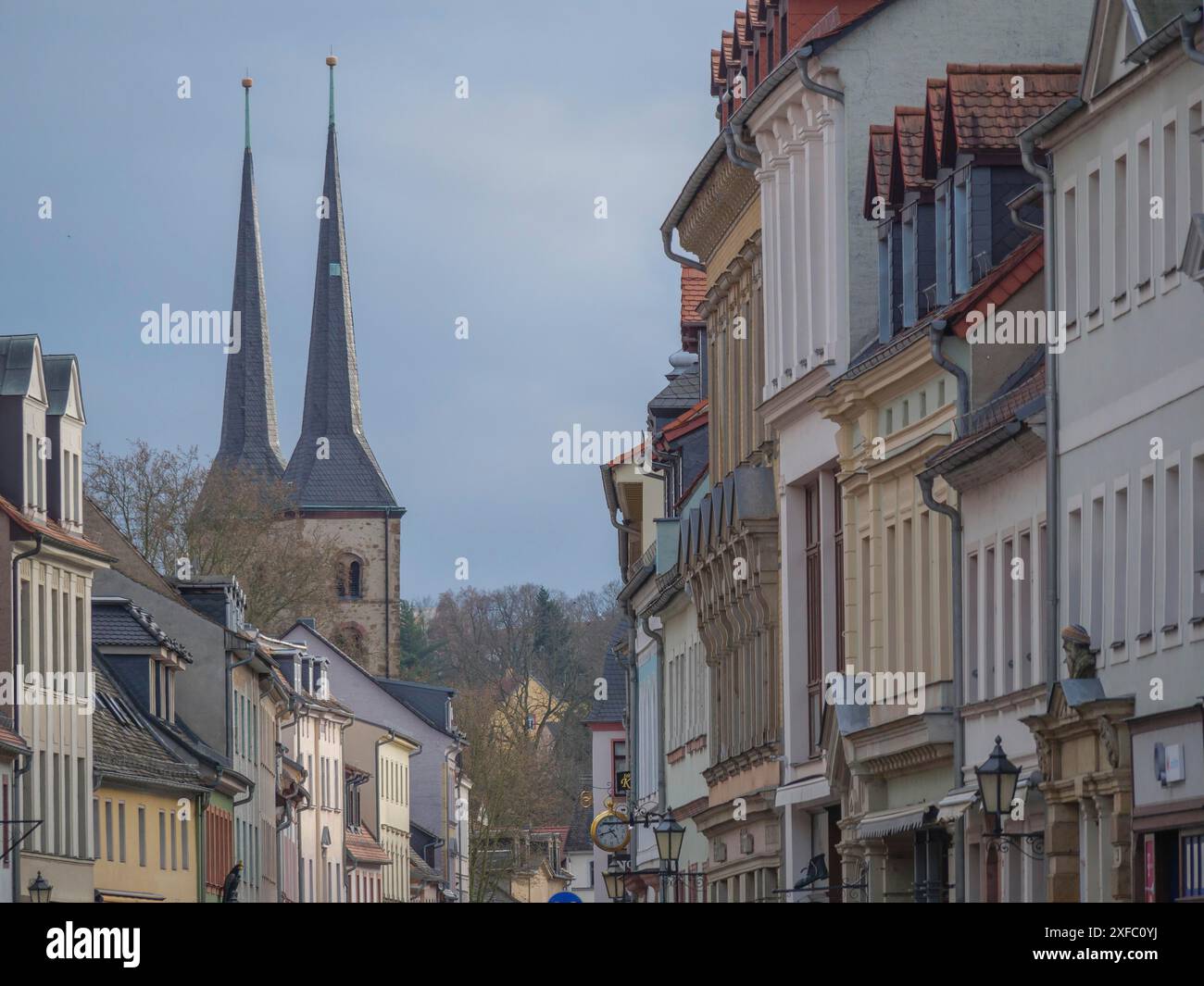 Stadtstraße gesäumt von historischen Gebäuden und Türmen, die unter teilweise bewölktem Himmel in den Himmel ragen, grimma, dresden, deutschland Stockfoto