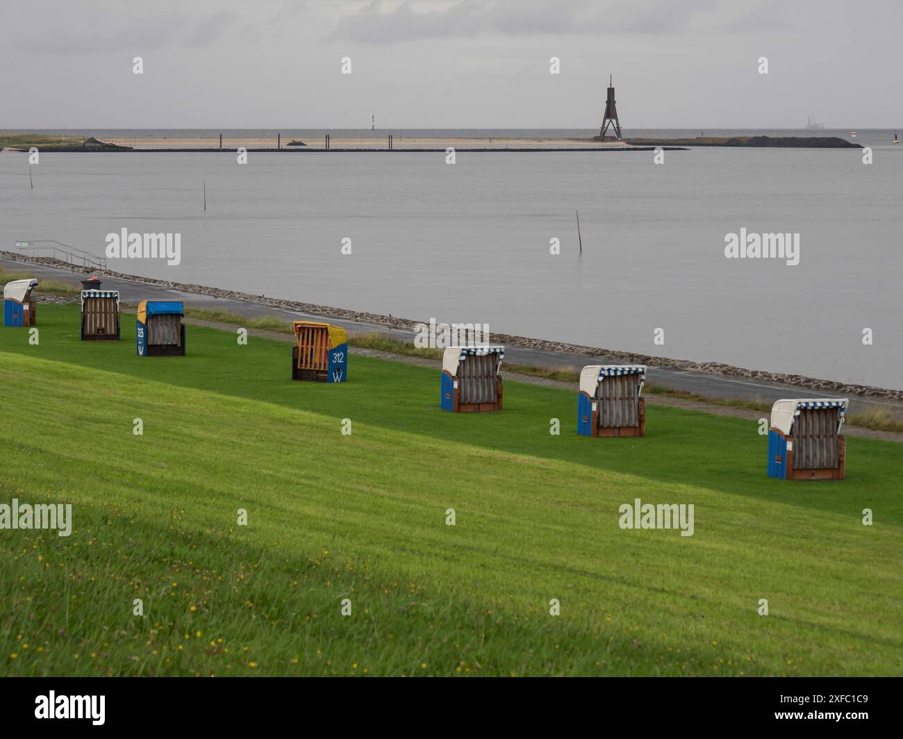 Liegestühle auf einer grünen Wiese am Meer, mit einem Leuchtfeuer im Hintergrund, cuxhaven, deutschland Stockfoto