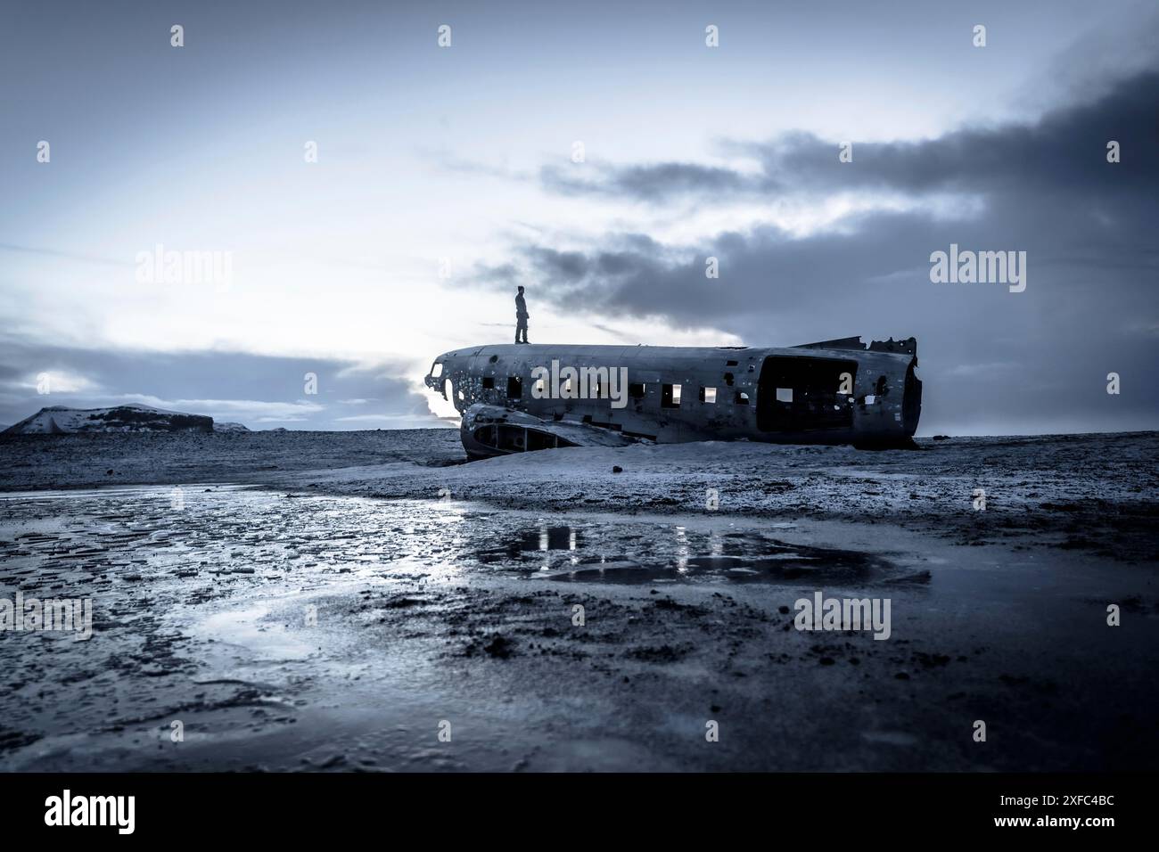 Ein Mann auf dem abgestürzten Militärflugzeug in Solheimasandur im Winter mit dem gefrorenen Boden Stockfoto