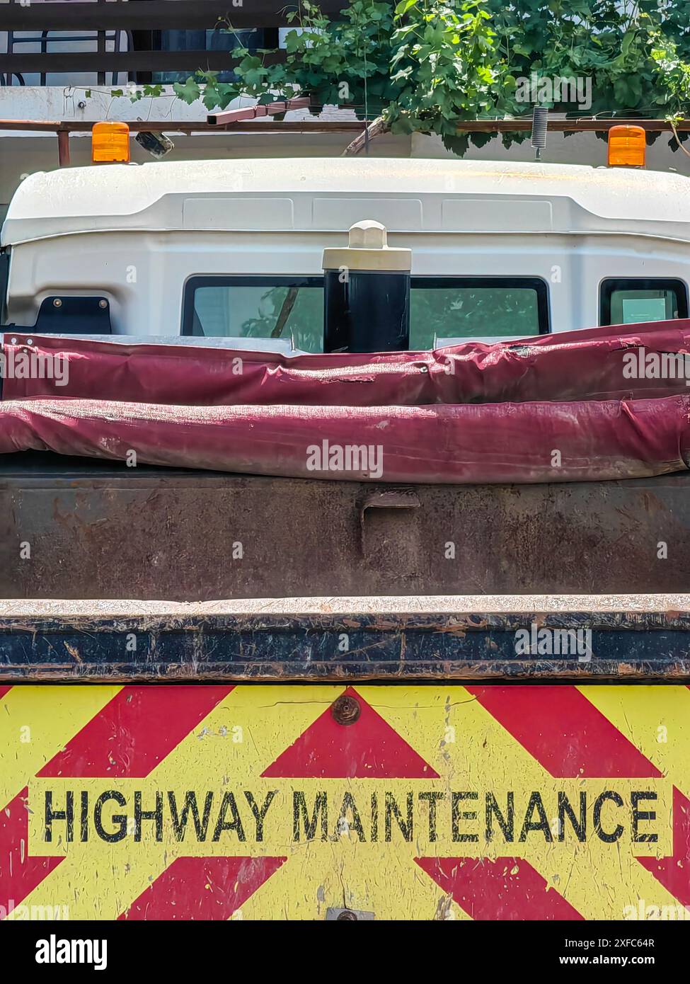 In Bearbeitung. Straßenwartung, schwarze Buchstaben auf rotem und gelbem Lkw-Anhänger. Stockfoto