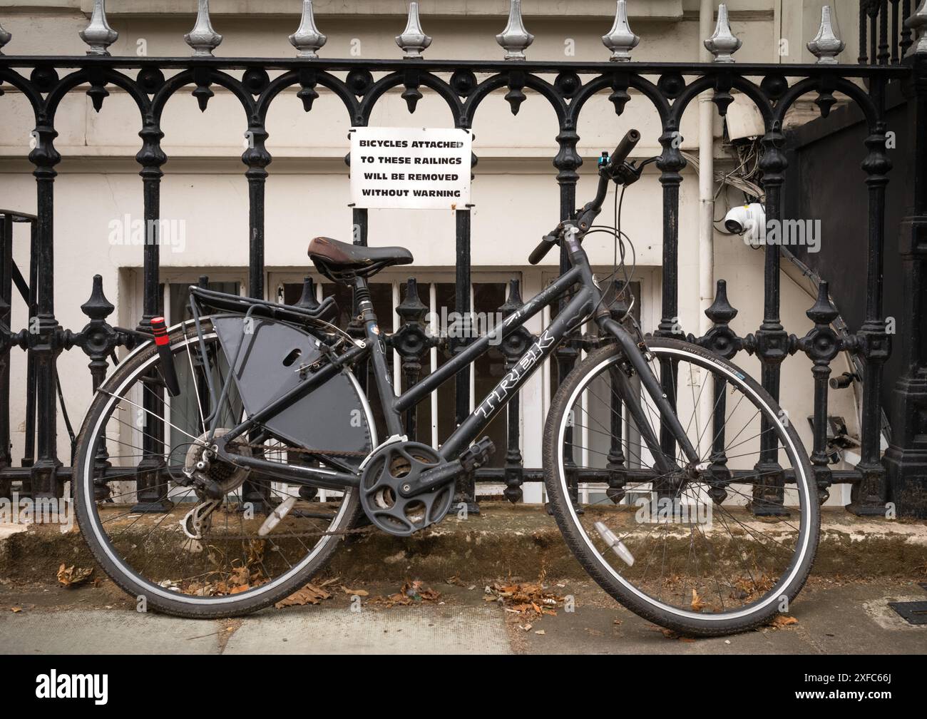 London / UK - 28. Juni 2024: Ein Fahrrad ist an Geländern befestigt, die eine Warnung enthalten, keine Fahrräder anzubringen. Stockfoto