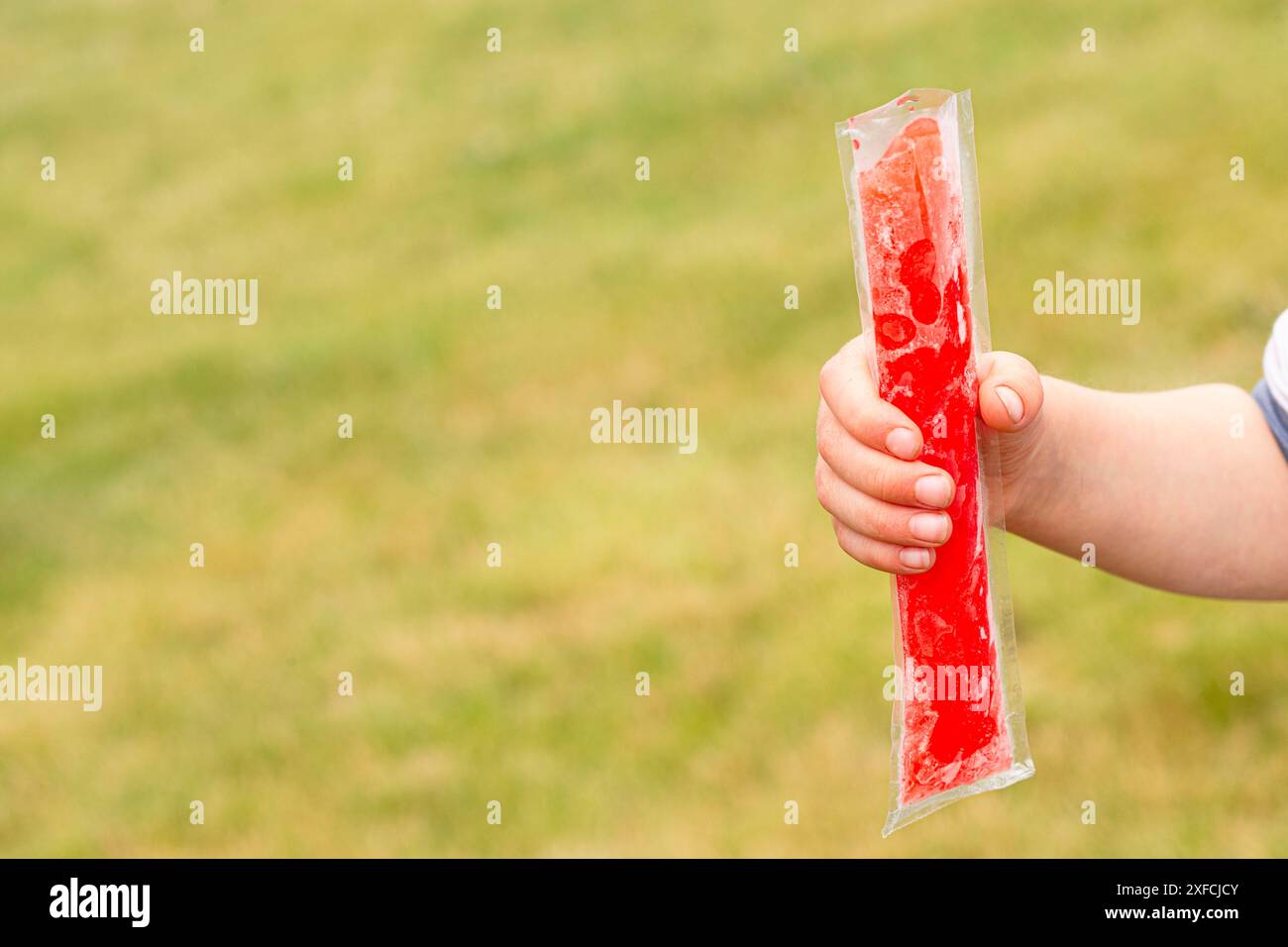 Ein kleines Kind, das einen gefrorenen Eispops hält Stockfoto