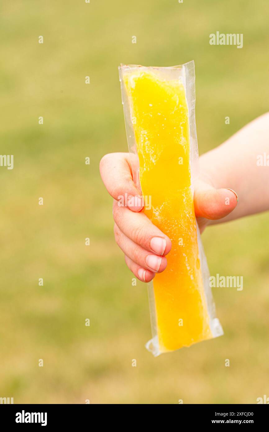 Ein kleines Kind, das einen gefrorenen Eispops hält Stockfoto
