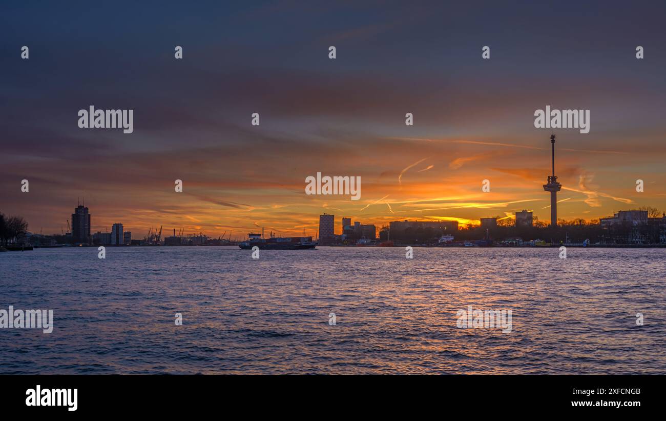 Sonnenuntergang über der Maas in Rotterdam mit der Silhouette des Hafens und Euromast im Hintergrund Stockfoto